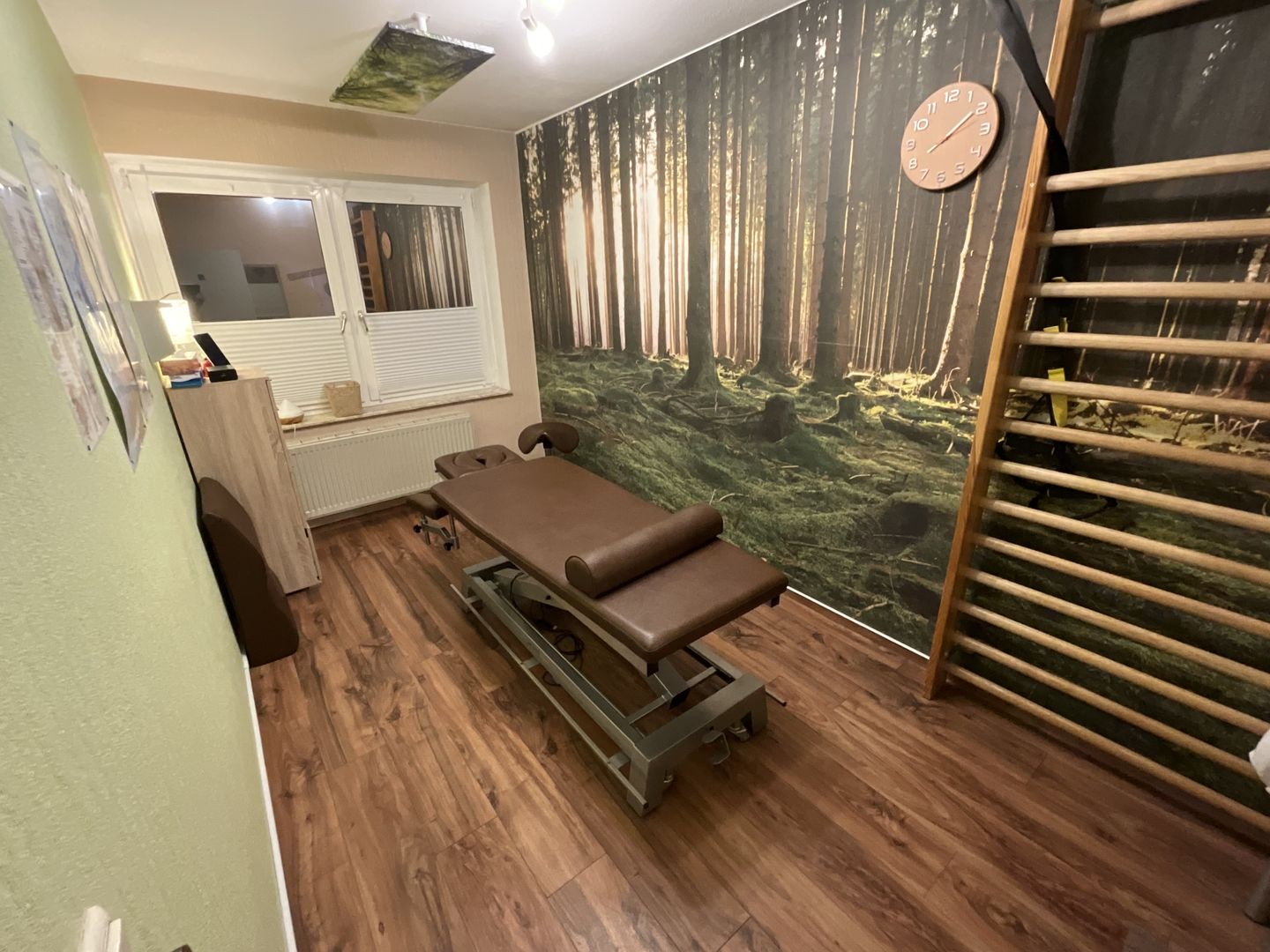 Therapieraum mit Holzfußboden und einer Wand, die eine friedliche Waldlandschaft darstellt.